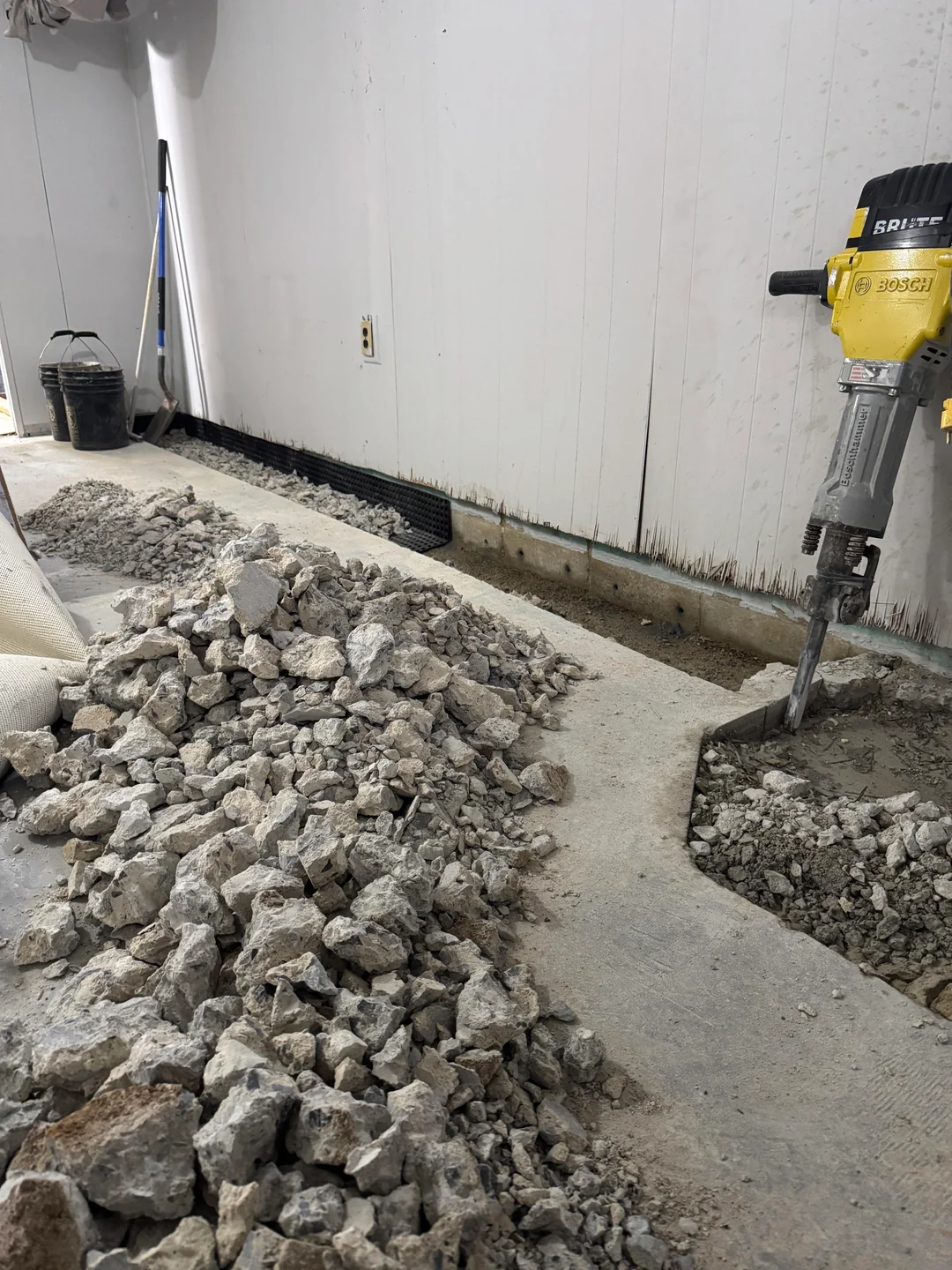 Basement waterproofing Portland OR cost, a crew installing an interior drainage system